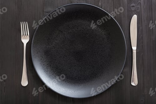 Preview: top view of black plate with knife, spoon on dark