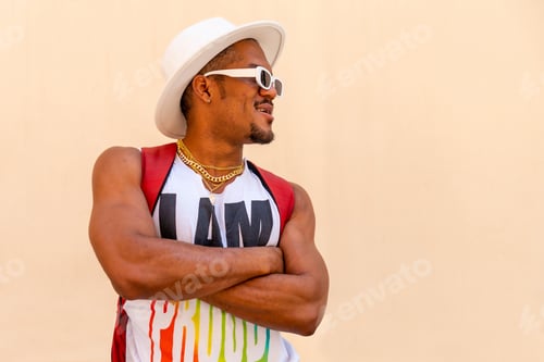 Preview: Black gay man at pride party on cream wall, LGBT flag, facing right