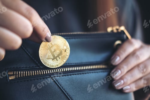 Preview: Closeup image of a woman picking up and dropping bitcoin into a black wallet
