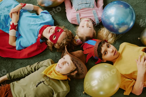 Preview: Group of Children in Costumes Lying on Floor Celebrating Birthday Party