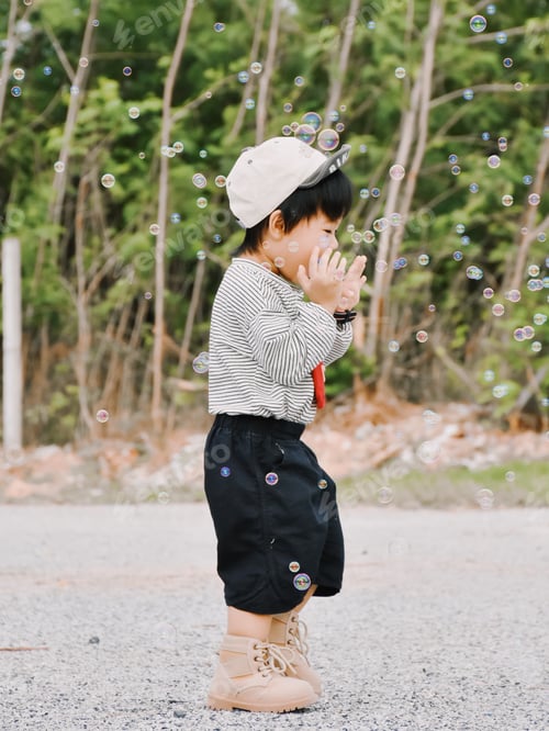 Preview: Little boy child playing with soap bubbles outdoors in sunny spring day.
