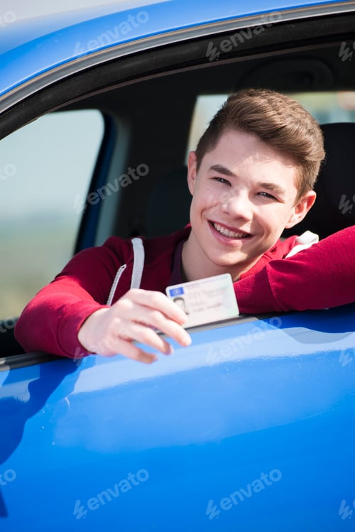 Preview: Teenager sitting in car showing driving license, partial view