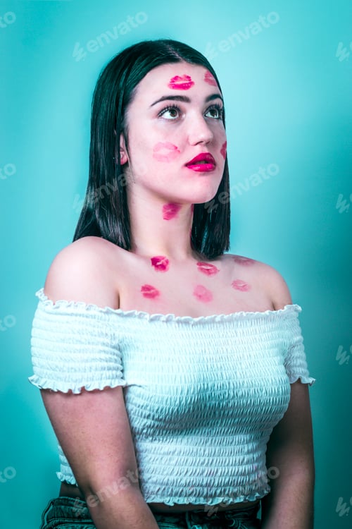 Preview: Teen girl with red lipstick kiss marks across her face.