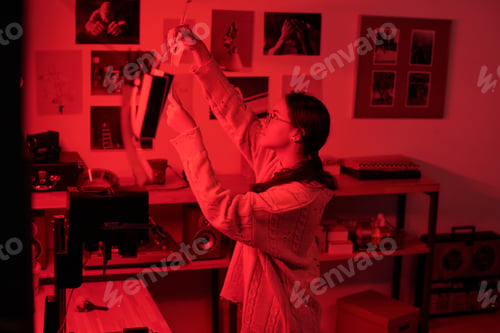 Preview: Female Photographer Hanging Photo Prints to Dry in Darkroom Working