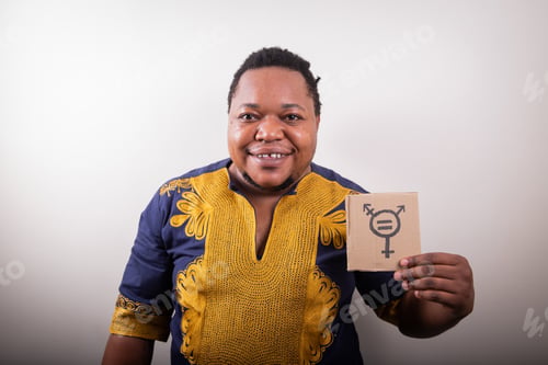 Preview: Studio portrait of an African trans person holding a cardboard with the trans symbol