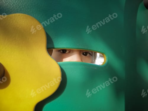 Preview: Little girl peeking from at the playground.