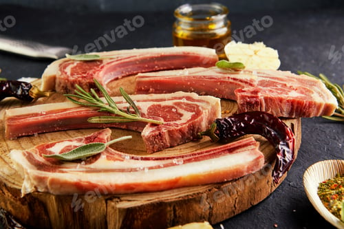 Preview: Raw lamb ribs with ingredients for cooking: salt, pepper, olive oil and herbs on a wooden stand