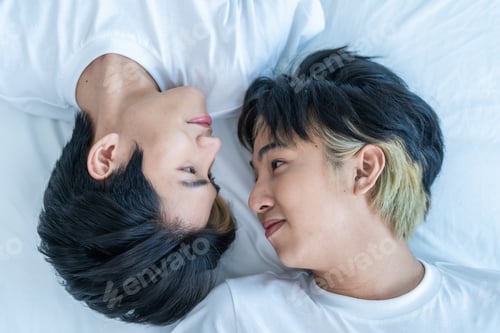 Preview: Asian happy man gay family lying down on bed and look at each other.