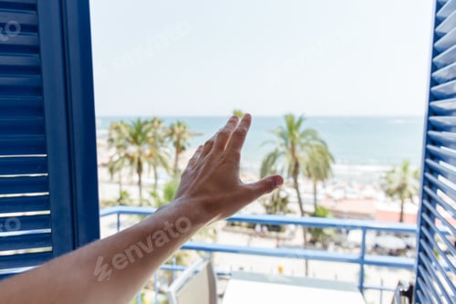 Preview: Cropped view of male hand near open door with sea coast and palm trees at background in Catalonia,