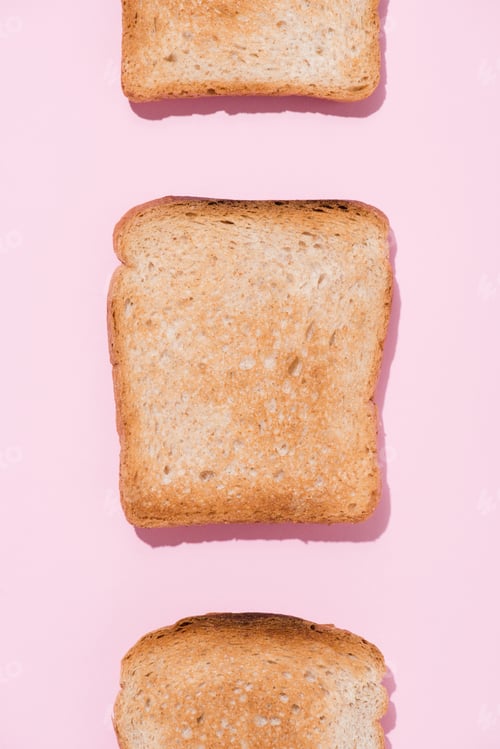 Preview: top view of row of crunchy toasts on pink surface