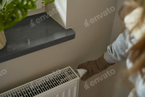 Preview: Close up of woman trying to turn the heat up on home radiator heater