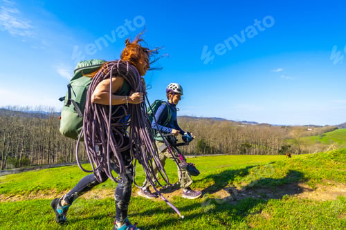 Preview: Climbers walking on mountain meadow carrying climbing rope and gear