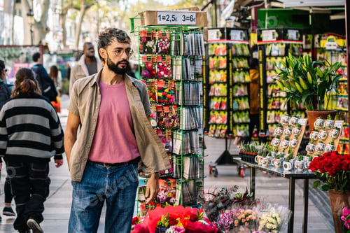 Preview: Man walking and looking at flower and seed packets display in outdoor market