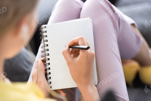 Preview: selective focus of woman writing in empty textbook
