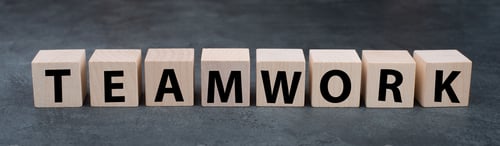 Preview: The word teamwork is standing on wooden cubes, dark background, working in a team, business concept