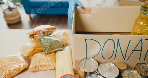 Preview: Donations food with oil, canned food, pasta, tomato paste on the wooden table.