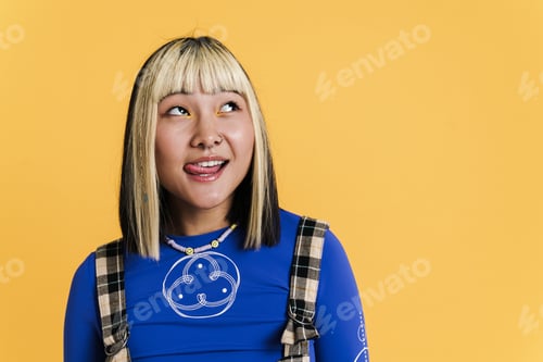Preview: Asian girl with piercing showing her tongue and looking aside