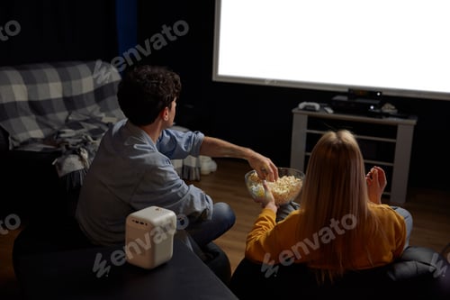 Preview: Back view of couple watching movie with popcorn together
