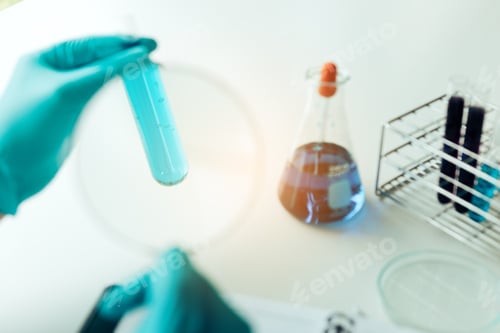 Preview: Chemist or scientist using magnifying glass dispense the solution in a glass jar.