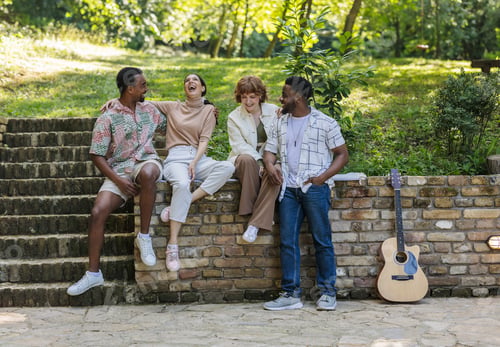 Preview: Multiracial friends enjoying vacation, laughing together in a park