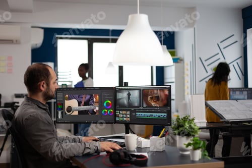 Preview: Video editor cuting footage working at film editing montage on computer with dual monitors setup
