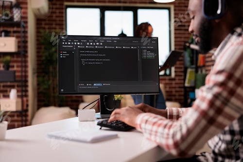 Preview: Freelance programmer with wireless headphones writing code on personal computer while girlfriend is