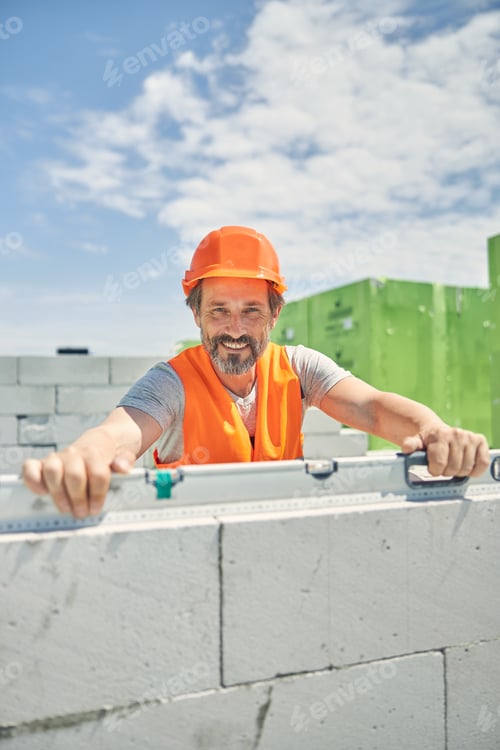 Preview: Man with hands on a spirit level looking ahead