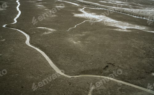 Preview: Landscape of coastal mud. Loneliness. Beach on tide. Water canal with natural pattern. Grey clay.
