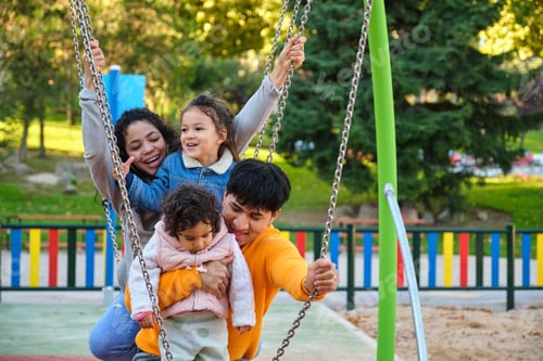 Preview: Hispanic family with two children playing together in a playground.