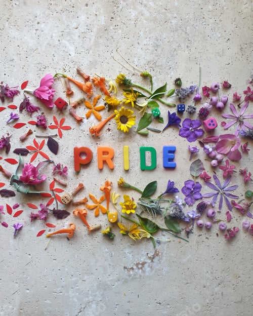 Preview: pride, word made with flowers on stone table