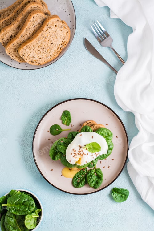 Preview: Appetizing bruschetta with poached egg and spinach on a plate.