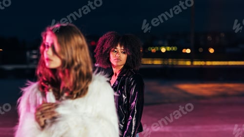 Preview: One young girl stands behind the other and looking down