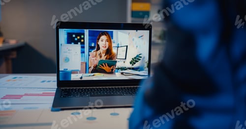 Preview: Asia businesswoman using laptop talk to colleagues about plan in video call meeting at living room.