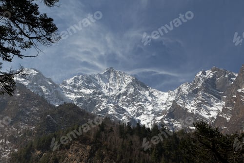 Preview: Majestic snow-capped mountains tower over lush green forest in the himalayas on a sunny day