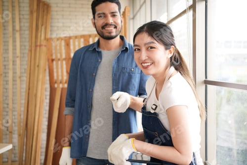 Preview: Portrait of happy carpenters designing and planing wood products in workshop
