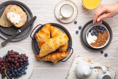 Preview: Breakfast setting with woman eating granola with yoghurt and berries