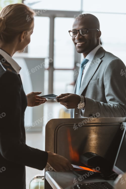 Preview: smiling handsome businessman giving passport to staff at airport check in counter