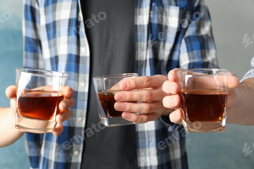 Preview: Men drink, cheers. Glasses of whiskey against blue background, close up