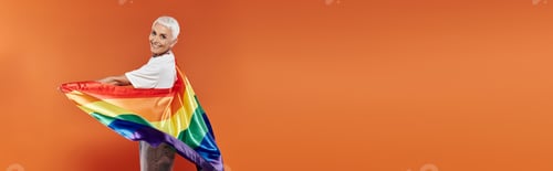 Preview: Confident Lesbian Celebrating Pride With a Rainbow Flag Against Vibrant Orange Background
