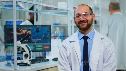 Preview: Microbiologist sitting in laboratory looking at camera