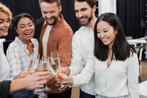 Visualização: Empresária asiática sorridente tocando champanhe com colegas multiétnicos no escritório
