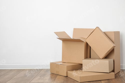 Preview: Pile of cardboard boxes near white wall indoors. Space for text