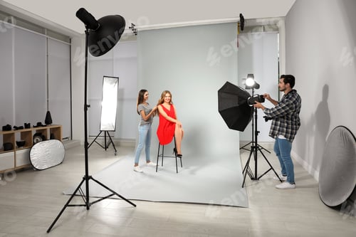 Preview: Professional photographer and assistant working with model in modern studio