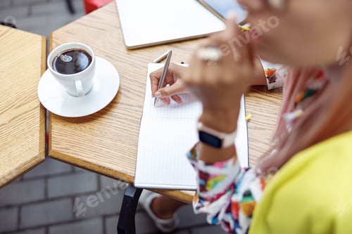 Preview: Person writing with steel pen in notepad near coffee cup