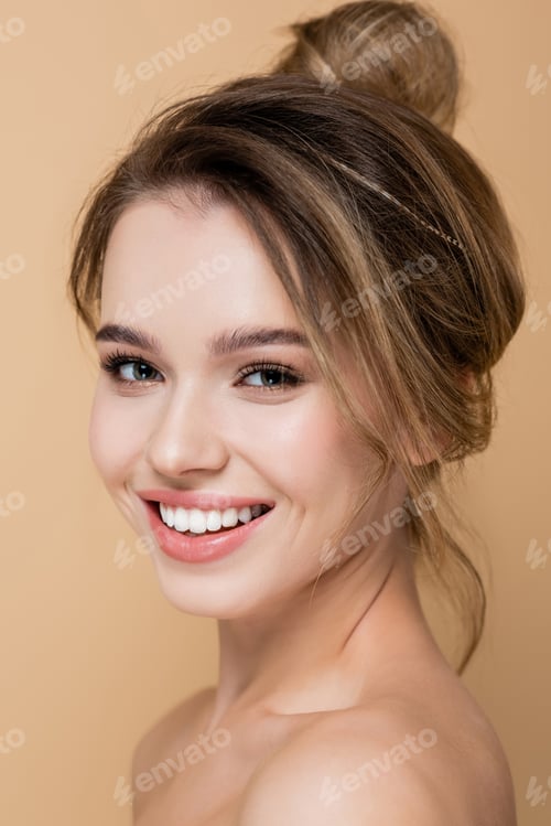 Preview: close up view of charming woman with natural makeup smiling at camera isolated on beige