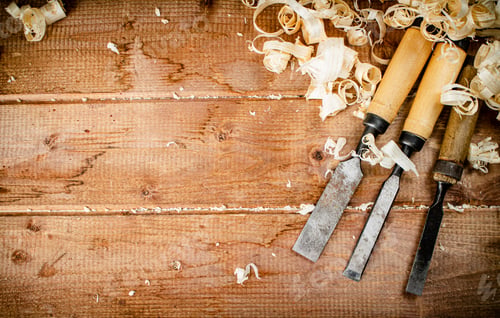 Preview: Chisels with wooden shavings. On a wooden background.