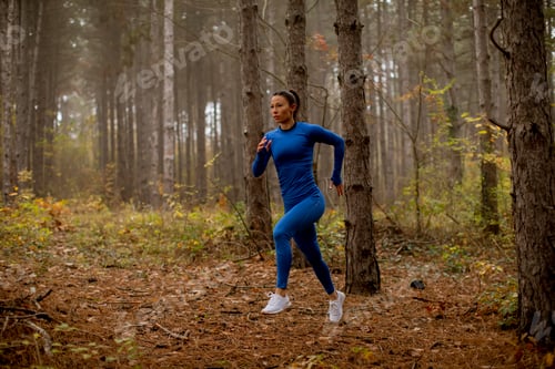 Preview: Young woman running on the forest trail at autumn