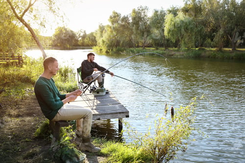 Preview: Friends fishing on wooden pier at riverside. Recreational activity
