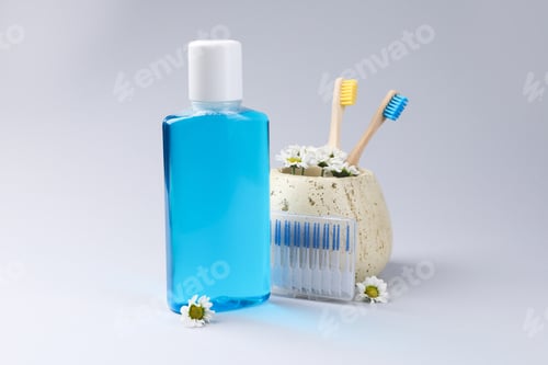 Preview: Composition with fresh mouthwash in bottle, toothbrushes and interdental brushes on grey background