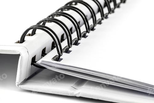 Preview: Macro photo of a white notebook with a black metal spiral connecting the pages.